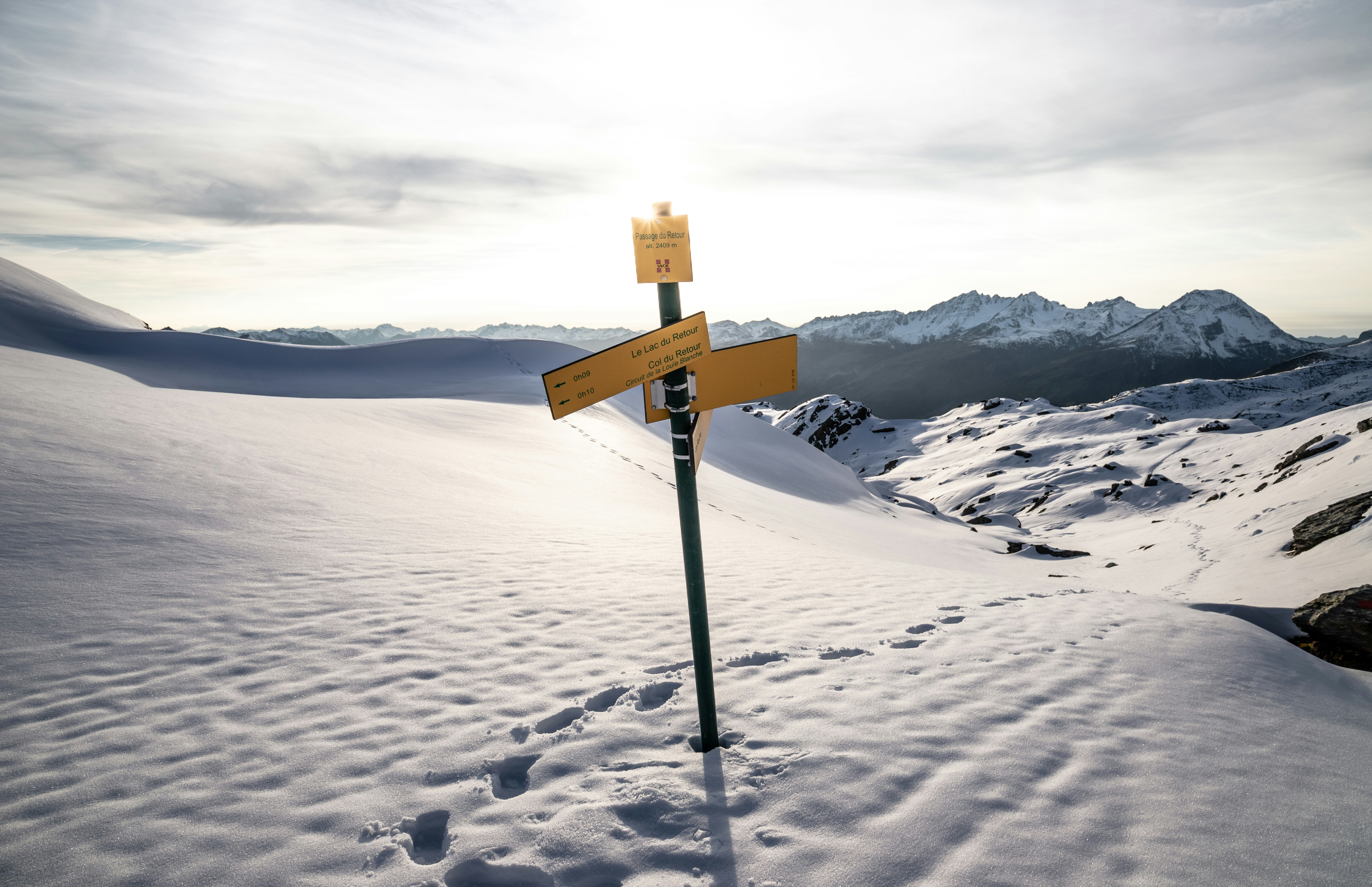 brown wooden signage on snow covered ground during daytime